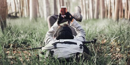 Mann liegt mit Smartphone im Wald