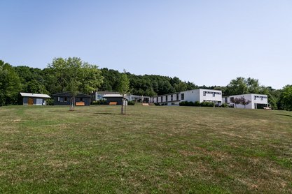 Grüne Wiese mit Schullandheim im Hintergrund