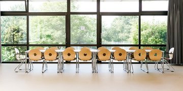 Großer heller lichtdurchfluteter Raum mit einem langen Tisch und Stühlen