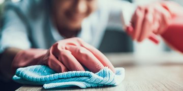 Frau mit Handschuhen reinigt eine Oberfläche
