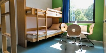 Schlafraum mit zwei Hochbetten und einer Sitzgelegenheit