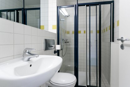 Badezimmer mit Waschbecken unter Spiegel neben Toilettte und begehbarer Duschkabine 