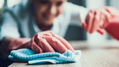 Frau mit Handschuhen reinigt eine Oberfläche