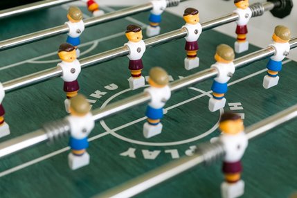 Grüne Tischfußballplatte mit Fußballmännchen an Schiebestangen 