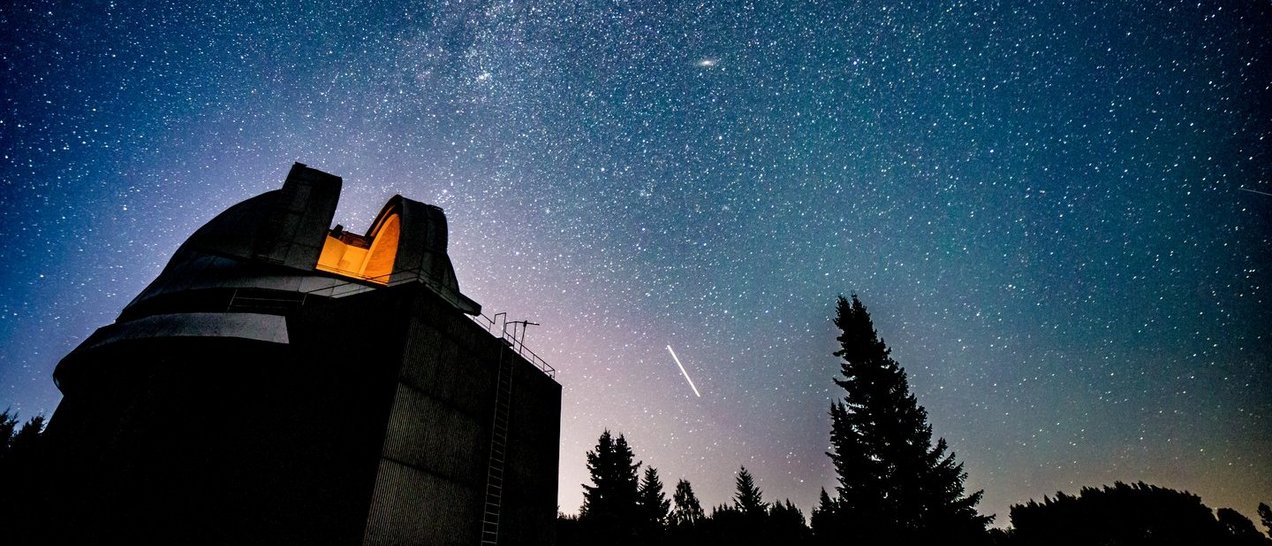 Blick auf eine Sternwarte vor einem sternenbehangenen Nachthimmel